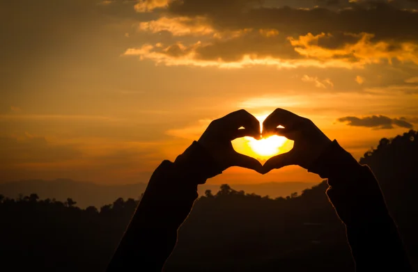 Siluetas de mano en forma de corazón con puestas de sol . — Foto de Stock