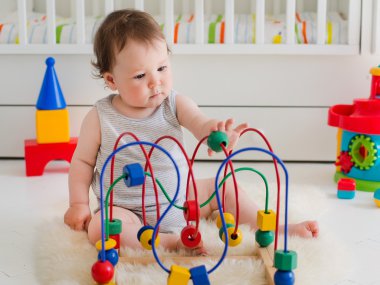 Küçük kız çocuk odasında eğitici oyuncaklarla oynuyor.