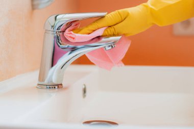 Kadınlar evlerindeki banyoda ev işlerini yapıyor. Temizlik işleri. Deterjan köpükleriyle lavabo ve musluk temizliyor..