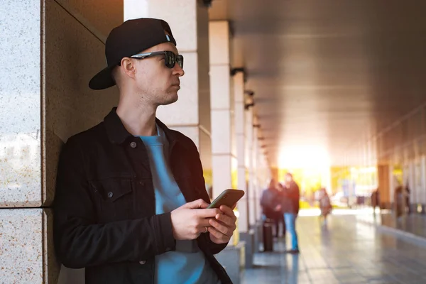 Moda elegante chico negro gorra gafas de sol con auriculares smartphone fondo urbano atardecer — Foto de Stock