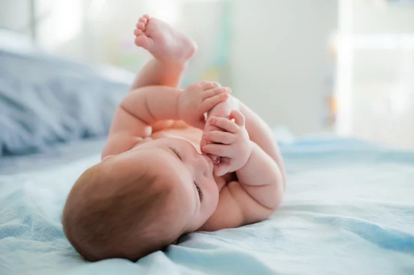 Baby plays with own feet — Stock Photo, Image