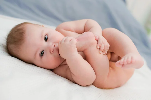 Baby plays with own feet — Stock Photo, Image