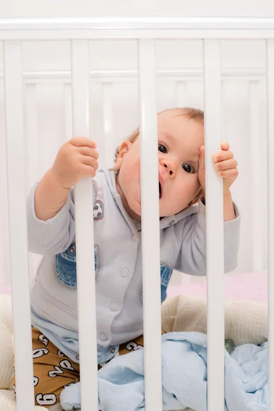 Ребенок кусает кровать за решеткой — стоковое фото
