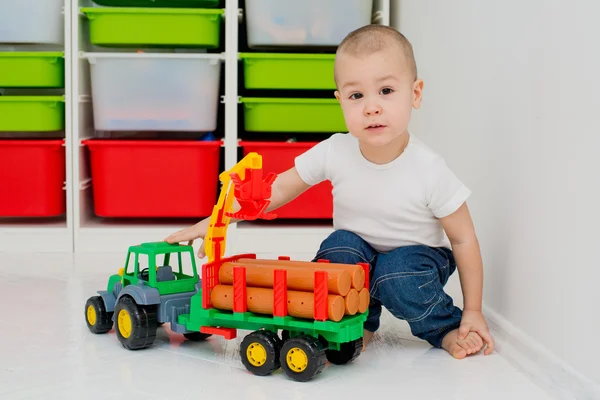 Criança brinca com um caminhão de madeira — Fotografia de Stock