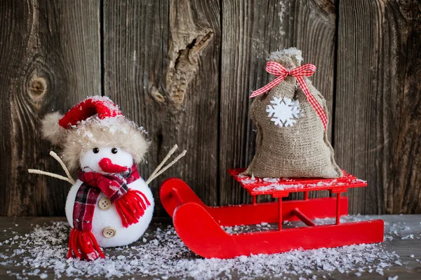 Muñeco de nieve y una bolsa en trineo — Foto de Stock