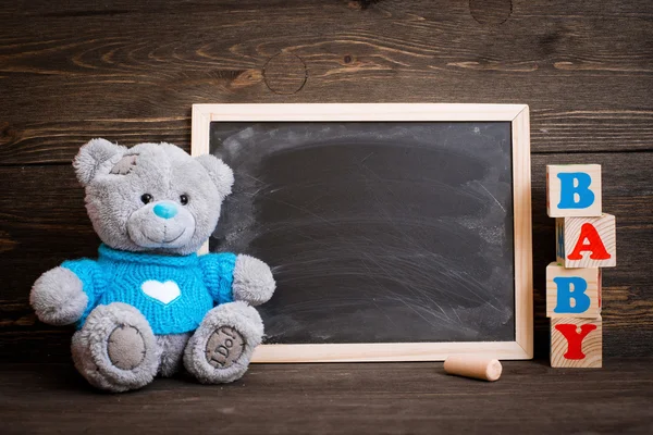 Chalk board and  teddy bear on a wooden background — Stock Photo, Image