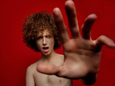 Stüdyoda poz veren kıvırcık saçlı erkek model.