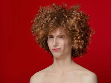 Stüdyoda poz veren kıvırcık saçlı erkek model.