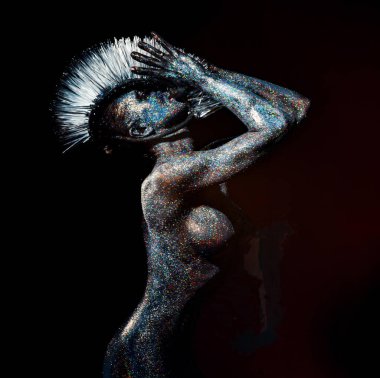 Mohawk ve parlak metalik parıltılarla kaplı atletik figürlü kadın model. 