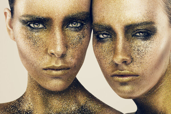 Women faces in gold glitters Stock Picture