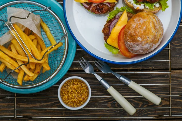 Hamburgers with vegetables, french fries and mustard — Stock Photo, Image