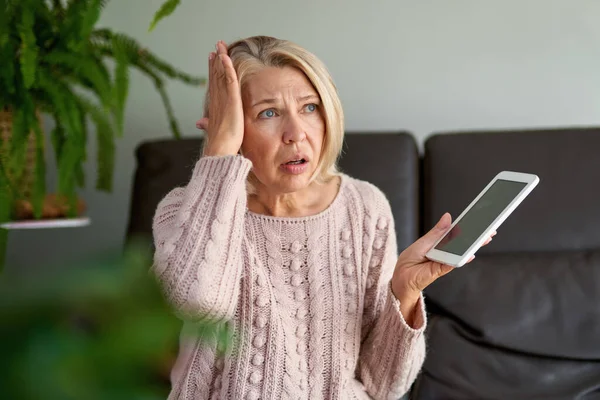 Traurige reife Frau, die auf der Couch sitzt und ein digitales Tablet benutzt. Zu Hause über Tablet im Internet surfen. — Stockfoto