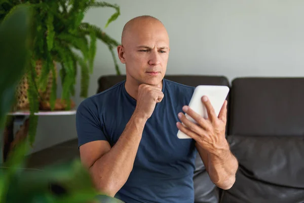 Ο άνθρωπος κάθεται στον καναπέ και χρησιμοποιεί ψηφιακή ταμπλέτα. Περιήγηση στο διαδίκτυο μέσω tablet στο σπίτι. — Φωτογραφία Αρχείου