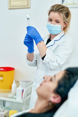 Elinde şırıngayla güzellik uzmanı portresi. Kozmetik uzmanı tıbbi aletleri tutuyor. Güzellik kliniği ya da hastane.