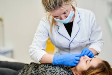 Dudak büyütme. Doktor kozmetik uzmanı güzellik salonunda güzel bir kadının dudak büyütme ameliyatını yapıyor..