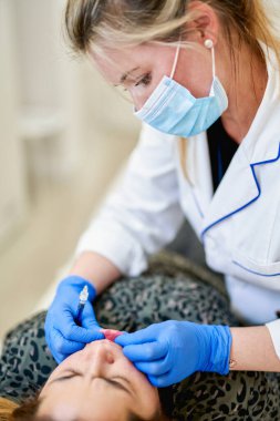 Dudak büyütme. Doktor kozmetik uzmanı güzellik salonunda güzel bir kadının dudak büyütme ameliyatını yapıyor..