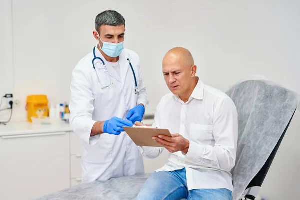 Treatment assignment.Man signing contract with doctor at hospital.