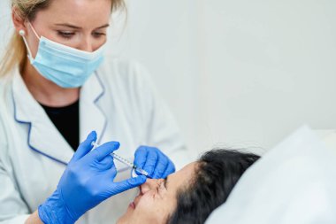 Kırışıklıklarla, karga ayaklarıyla, botoksla, ameliyat sırasında beyaz bir kadının portresiyle yüz kırışıklıklarını gidermek için, kozmetik cilt kozmetiğine enjekte edilir..