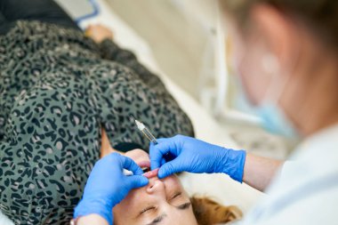 Dudak büyütme. Dudak için güzellik iğnesi yaptıran kadın. Doktor kozmetik uzmanı güzellik salonunda güzel bir kadının dudak büyütme ameliyatını yapıyor..