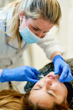 Doktor kozmetik uzmanı güzellik salonunda güzel bir kadın için Lip 'in geliştirme prosedürünü uyguluyor.