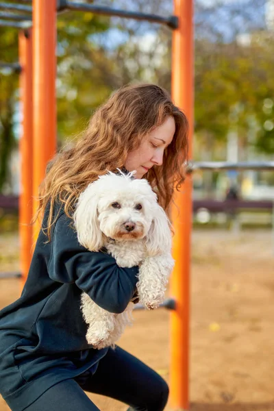Chica haciendo ejercicios con un perro en sus manos — Foto de Stock