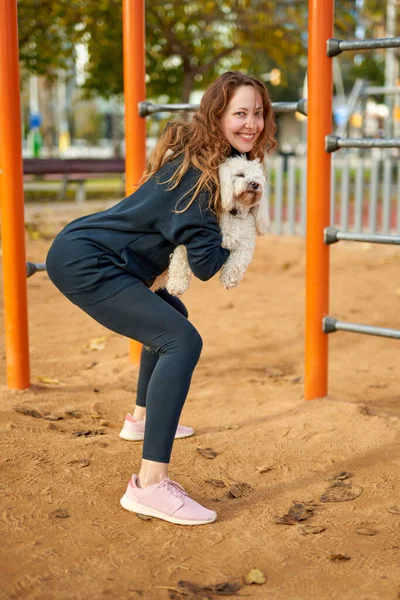 Chica haciendo ejercicios con un perro en sus manos — Foto de Stock