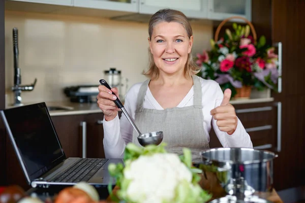 Mature woman in kitchen preparing food. — Stock Photo, Image