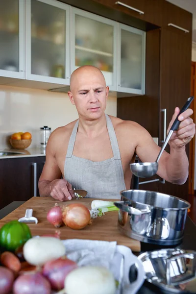 Adult brutal man in kitchen preparing food — Stock Photo, Image