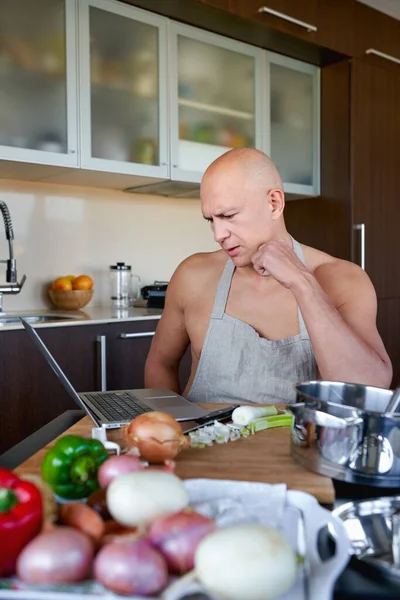 Man looking recipe on laptop in kitchen at home. — Stock Photo, Image