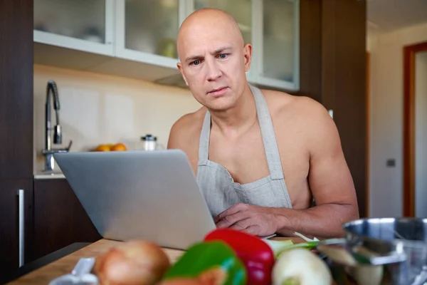 Homem procurando receita no laptop na cozinha em casa. — Fotografia de Stock