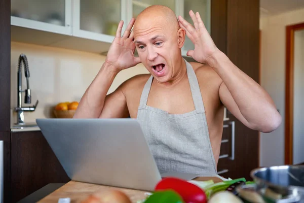 Homem procurando receita no laptop na cozinha em casa. — Fotografia de Stock