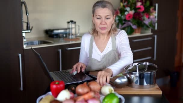 Старшая женщина приготовления пищи с помощью рецепта на ноутбуке. — стоковое видео