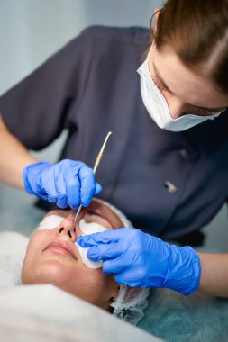 Doktor kozmetoloji kliniğinde güzellik prosedürü uyguluyor.