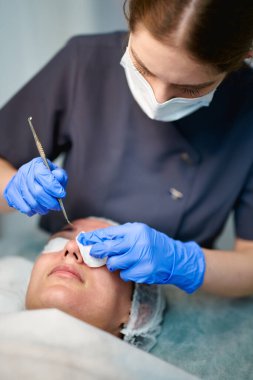 Doktor kozmetoloji kliniğinde güzellik prosedürü uyguluyor.