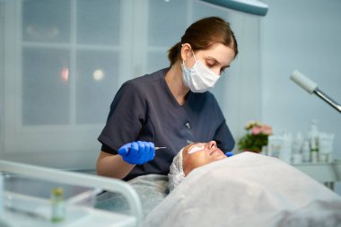 Güzellik uzmanı hastaların yüzlerine tedavi yöntemi uyguluyor. Doktor şırıngayla kadının alnına ilaç düşürüyor..