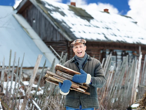 Mann in Winterkleidung trägt Brennholz — Stockfoto