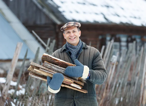 Glücklicher Mann mit einer Armvoll Brennholz — Stockfoto