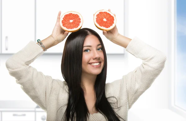 Смешная девушка держит цитрусовые на кухне — стоковое фото