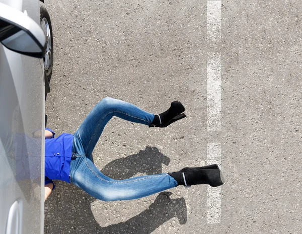 Femme couchée sous sa voiture — Photo