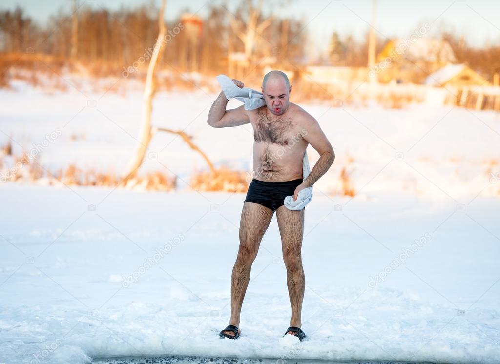man wipes towel after swimming in  freezing