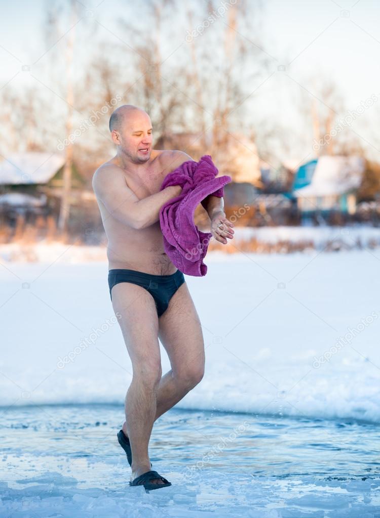man wipes a towel after swimming in  water at frosty morning