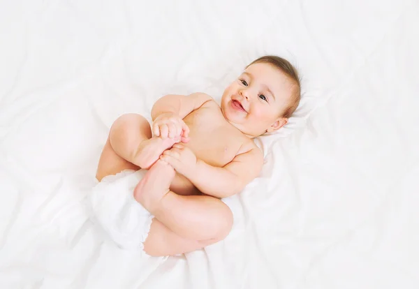 Bebê feliz em fralda jaz na cama — Fotografia de Stock