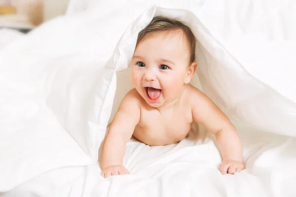 Surpreendido Bebê jaz na cama sob o cobertor — Fotografia de Stock