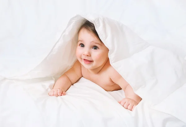 Surpreendido Bebê jaz na cama sob o cobertor — Fotografia de Stock