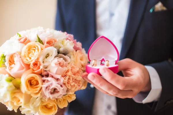 Wedding bouquet and rings on hand of groom — Stock Photo, Image