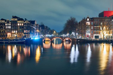Classic arch bridge over the canal at night to Amsterdam
