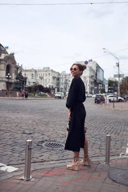 Woman in long black kimono and sunglasses in the city at the crossroads