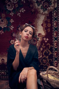 Cute girl in a black dress smokes a cigarette