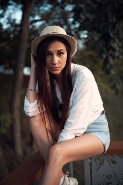 Gün batımında bir yaz parkında hasır şapkalı tatlı ve genç esmer.