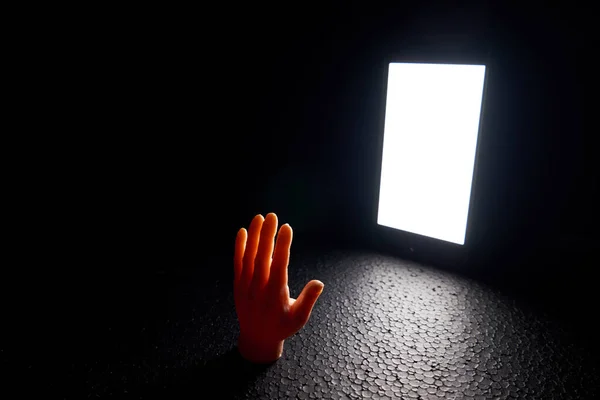 Hand in front of a large luminous smartphone screen in the dark